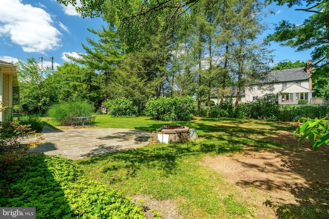 view of grassy yard with an outdoor fire pit and a patio