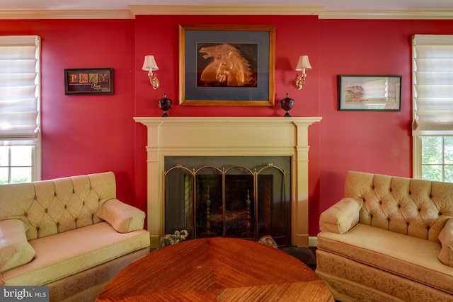 living area featuring a fireplace with flush hearth and crown molding