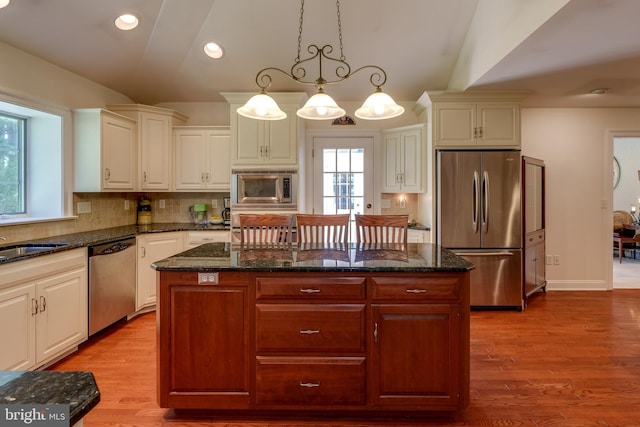 kitchen with stainless steel appliances, decorative backsplash, a kitchen island, decorative light fixtures, and recessed lighting
