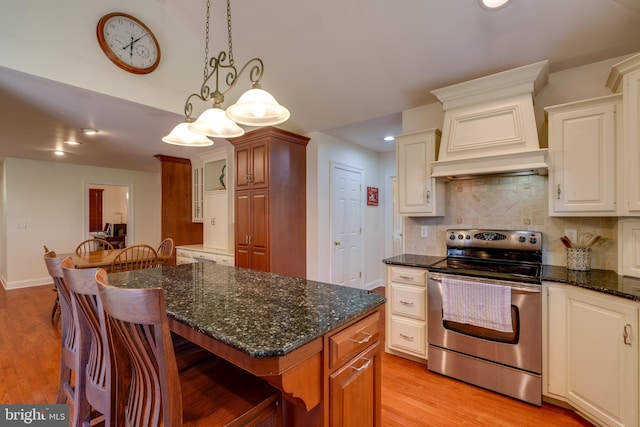 kitchen with stainless steel electric range, light wood finished floors, backsplash, a kitchen breakfast bar, and a center island