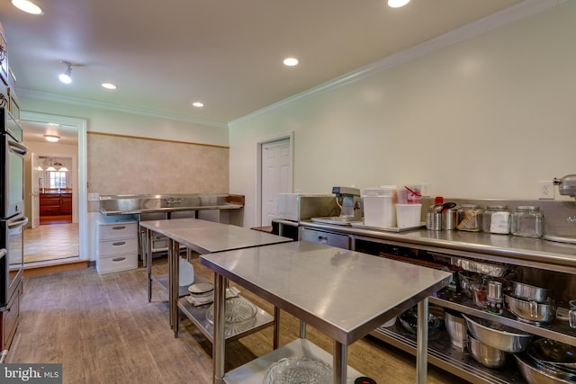 kitchen featuring stainless steel countertops, crown molding, wood finished floors, and recessed lighting