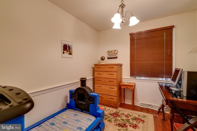 bedroom with a chandelier, wood finished floors, a desk, vaulted ceiling, and a wainscoted wall