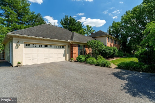 view of front of home with an attached garage, asphalt driveway, a shingled roof, and brick siding
