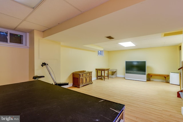 finished basement with a paneled ceiling, wood finished floors, and baseboards