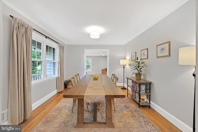 dining room with light wood-style floors, baseboards, and ornamental molding