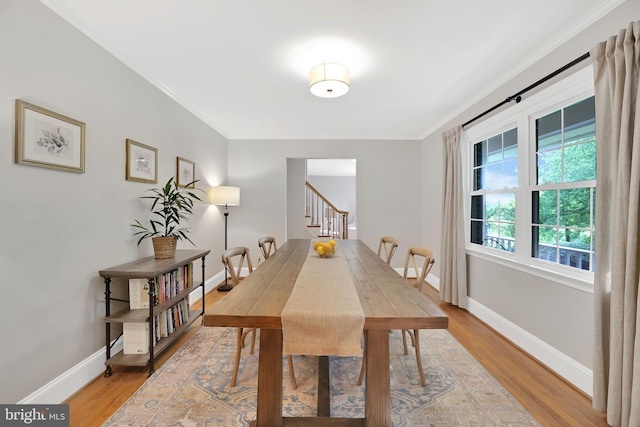 dining area with stairway, light wood-style floors, baseboards, and crown molding
