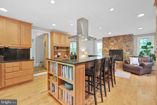 kitchen with island range hood, open shelves, light wood-style floors, a breakfast bar area, and recessed lighting