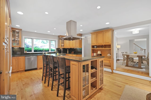 kitchen with stainless steel dishwasher, island exhaust hood, a kitchen breakfast bar, backsplash, and a kitchen island