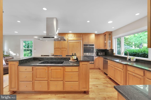 kitchen with island range hood, a sink, black appliances, a center island, and light wood finished floors