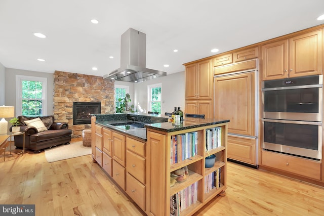 kitchen featuring double oven, island exhaust hood, plenty of natural light, light wood finished floors, and recessed lighting