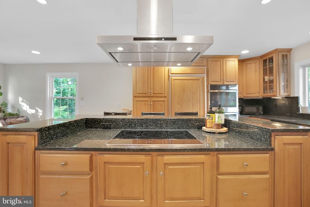 kitchen featuring black electric stovetop, island exhaust hood, recessed lighting, double oven, and dark stone countertops