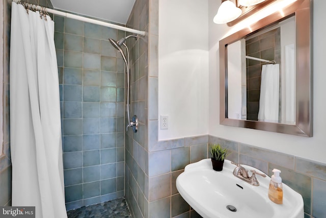 full bath featuring a sink, a tile shower, and tile walls