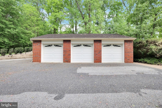 detached garage featuring view of wooded area