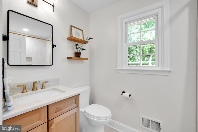 bathroom with toilet, vanity, baseboards, and a shower