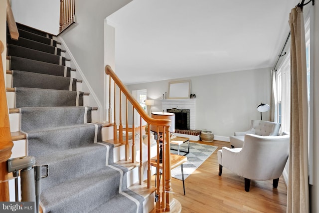 staircase featuring healthy amount of natural light, a brick fireplace, and wood finished floors