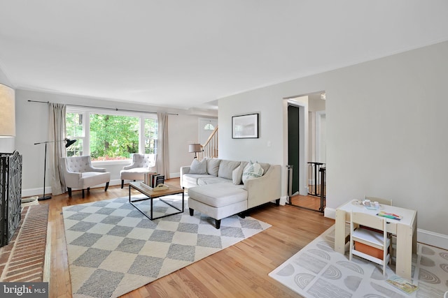 living room featuring light wood-style floors, stairs, and baseboards
