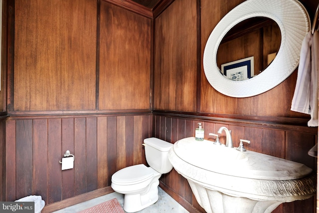 bathroom featuring toilet and wood walls
