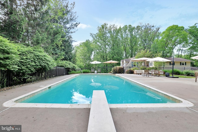 view of pool featuring fence, a diving board, and a patio area