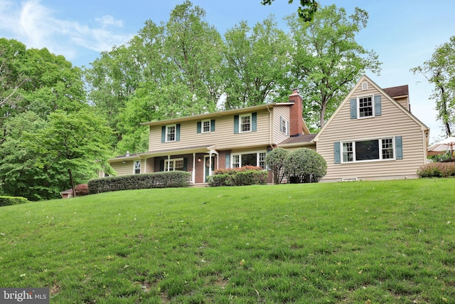 view of front facade with a chimney and a front lawn