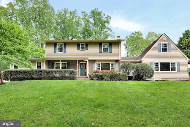 view of front of home featuring a front lawn, a chimney, and brick siding