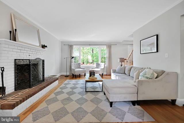 living area with light wood finished floors, crown molding, stairway, a fireplace, and baseboards