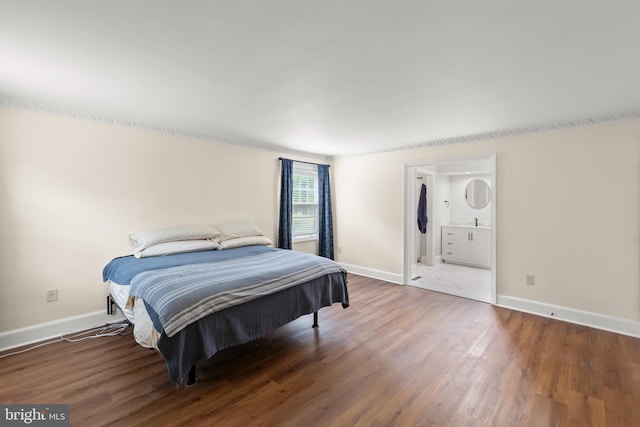 bedroom featuring wood finished floors, baseboards, and connected bathroom