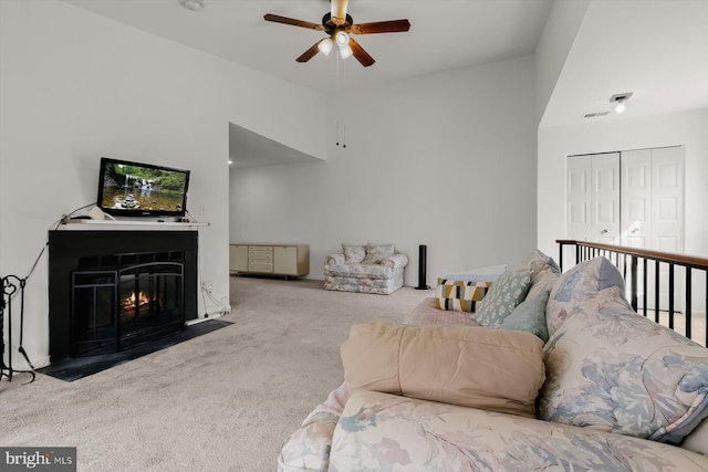 carpeted living area featuring a ceiling fan, a fireplace with flush hearth, and a high ceiling