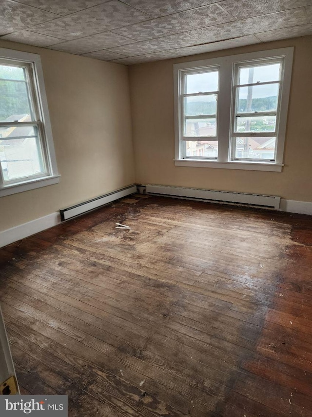 empty room featuring hardwood / wood-style floors, a baseboard radiator, and baseboards
