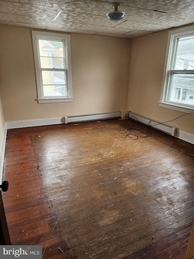spare room featuring hardwood / wood-style flooring, baseboard heating, healthy amount of natural light, and baseboards