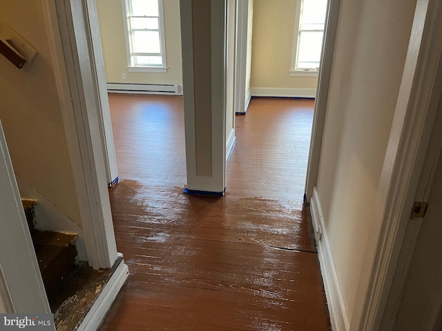 hall featuring wood-type flooring, a baseboard heating unit, baseboards, and stairway