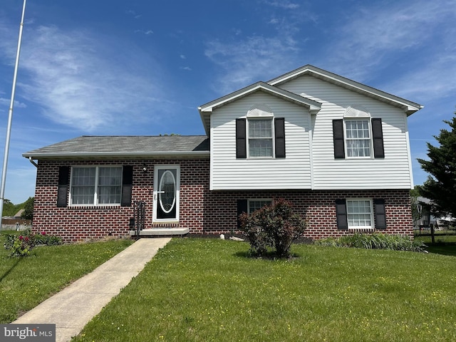 split level home with a front lawn, brick siding, and a shingled roof