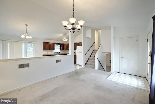 kitchen featuring freestanding refrigerator, a chandelier, lofted ceiling, ceiling fan, and pendant lighting