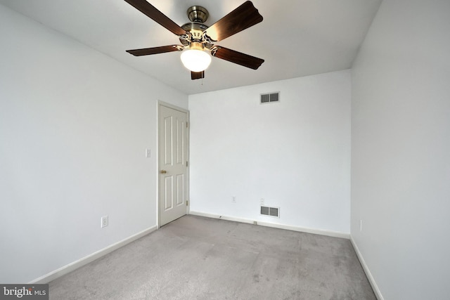 spare room with light colored carpet, baseboards, and a ceiling fan