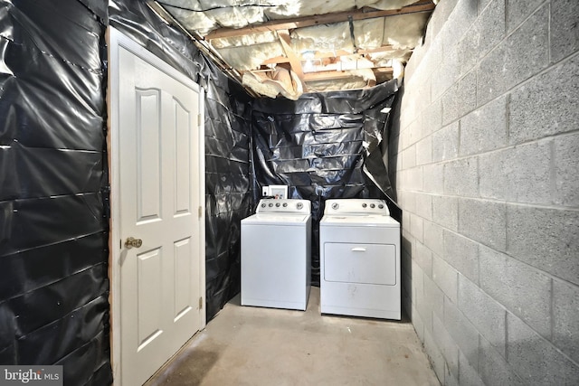 laundry room featuring washing machine and clothes dryer and concrete block wall