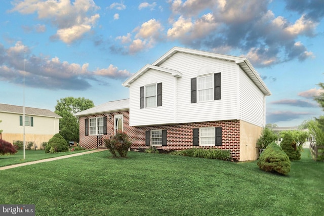 tri-level home featuring a front yard and brick siding