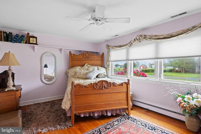 1 Somerset Ave, Cambridge, MD 21613 - bedroom with a baseboard heating unit, multiple windows, wood finished floors, and ceiling fan