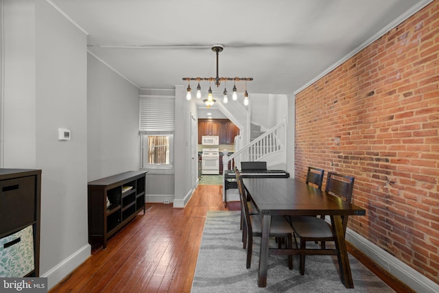 117 E Clement St, Baltimore, MD 21230 - dining room with baseboards, hardwood / wood-style floors, stairs, ornamental molding, and brick wall