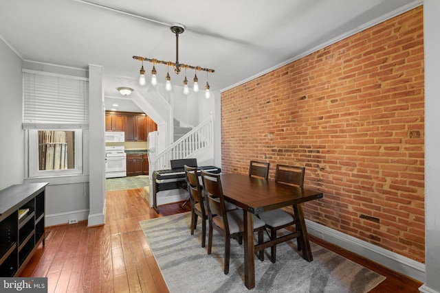 117 E Clement St, Baltimore, MD 21230 - dining area featuring stairs, baseboards, light wood-style flooring, brick wall, and ornamental molding