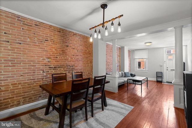 117 E Clement St, Baltimore, MD 21230 - dining space with decorative columns, brick wall, baseboards, hardwood / wood-style floors, and ornamental molding