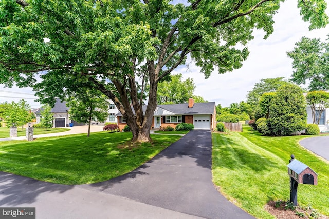 view of front facade with asphalt driveway, an attached garage, a front lawn, and a chimney