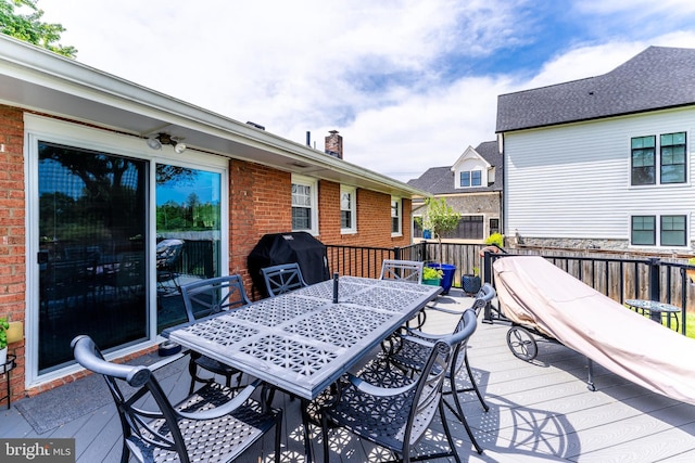 wooden terrace with outdoor dining space and grilling area