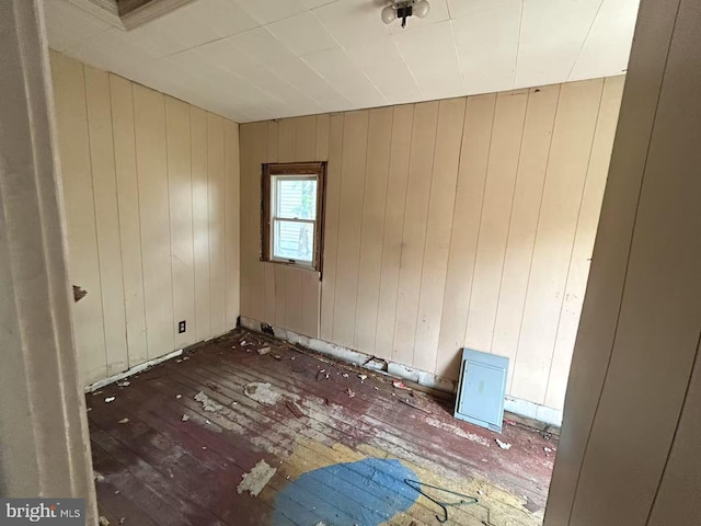 unfurnished room featuring hardwood / wood-style flooring and wooden walls