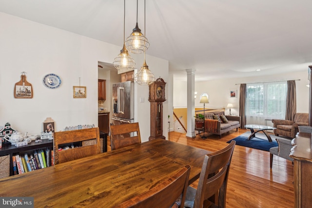 dining space featuring wood finished floors and decorative columns