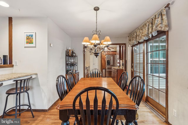 dining room with light wood-style flooring, a chandelier, and baseboards