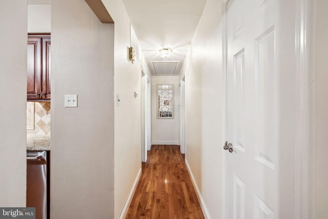 corridor featuring attic access, light wood-style floors, and baseboards