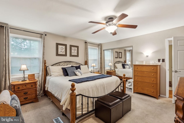bedroom with multiple windows, light colored carpet, and ceiling fan