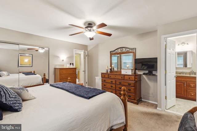 bedroom featuring light colored carpet, connected bathroom, a sink, and a ceiling fan