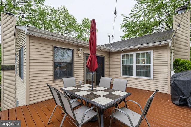 wooden deck with outdoor dining area and grilling area