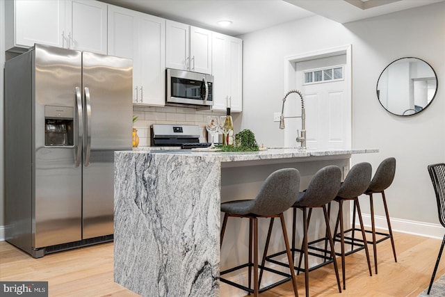3920 Mortimer Ave, Baltimore, MD 21215 - kitchen featuring stainless steel appliances, a sink, light wood-style flooring, and a breakfast bar area