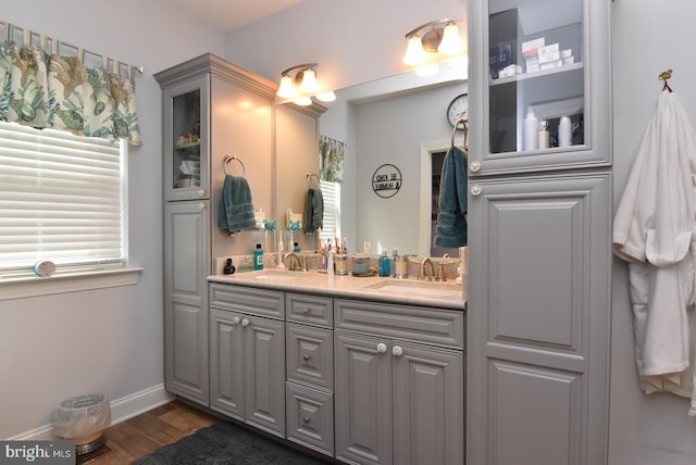 bathroom with wood finished floors, double vanity, and baseboards